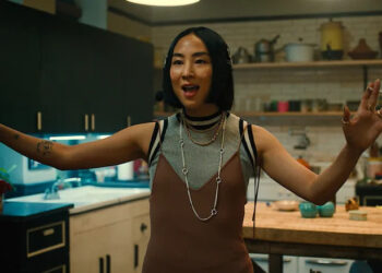 Maxine smoking a cigarette with her arms spread wide on Russian Doll