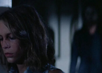 Laurie, tired, with Michael Myers standing behind her in Halloween (1978)
