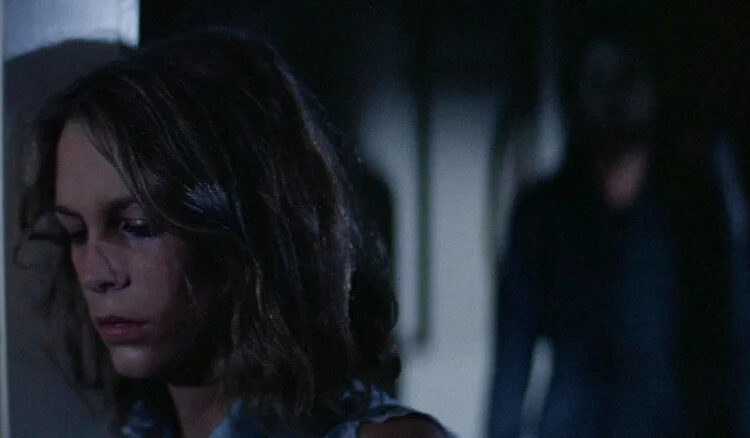 Laurie, tired, with Michael Myers standing behind her in Halloween (1978)