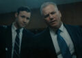 Sean Carrigan as John Douglas and Caleb Ruminer as Robert Ressler looking through a one-way mirror on Monster: The Ed Gein Story