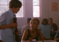Sarah Michelle Gellar's unnamed character sitting at a cafeteria table in