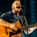 Country artist Zach Bryan singing onstage with intensity, reflecting the bold spirit of his track “Bad News” that challenges law enforcement and sparks debate.