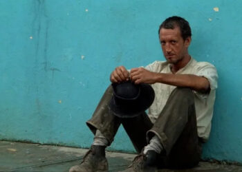 Roy Scheider as Jackie Scanlon in Sorcerer, looking really dirty and sitting against a blue wall.