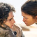 Two actors in a dramatic scene from a sci-fi film; one holds the other's face as they exchange an intense gaze