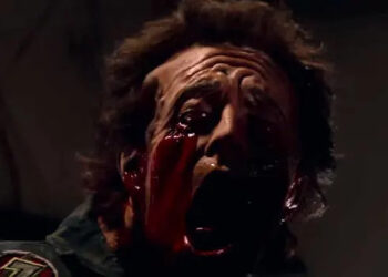 Close-up of a person in a horror scene, with a shocked expression and dramatic special effects makeup showing exaggerated injuries