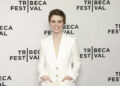 Sophia Lillis smiles in a white suit.