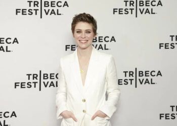 Sophia Lillis smiles in a white suit.