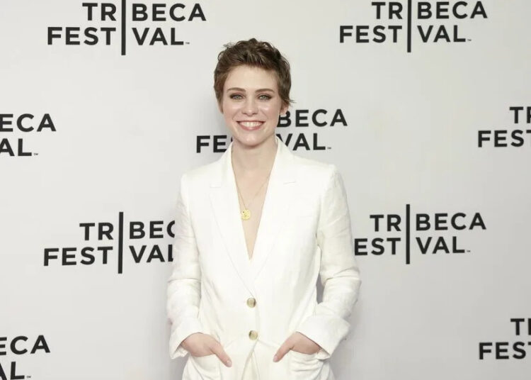 Sophia Lillis smiles in a white suit.