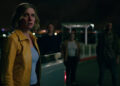 Rhea Seehorn as Carol Sturka looking worried beside a pickup truck with shadowy people in the background in Pluribus