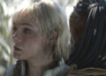 Elle Fanning as Thia looking to the side while attached to Dek in Predator: Badlands .
