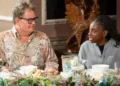 BBC/Studio Lambert/Euan Cherry A still publicity shot of Alan Carr and Cat Burns looking at each other slyly while sitting at a dinner table during episode five of the Traitors