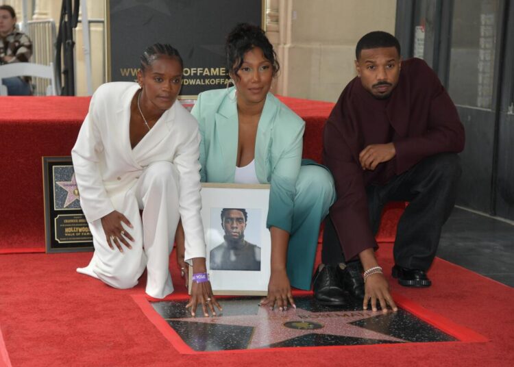 Letitia Wright, Simone Ledward Boseman and Michael B. Jordan kneel on Hollywood Walk of Fame, each with a hand on a new star