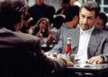 Robert De Niro as Neil McCauley sitting in a restaurant during the '90s thriller movie Heat. .