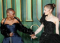 Cynthia Erivo and Ariana Grande holding hands and smiling at each other at a Wicked premiere