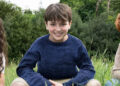 Arabella Stanton, Dominic McLaughlin and Alastair Stout smiling while crouching in a field