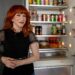 Kathy Griffin smiles in front of her neatly stocked fridge.