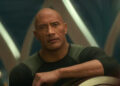Dwayne Johnson looks ahead in conversation with a stoic expression in Red One. .