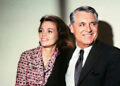 Cary Grant and a young Dyan Cannon sitting together and smiling not looking at the camera.