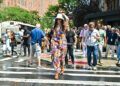 Hathaway holds on to her hat as she walks across a street.