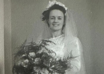 A woman in a white wedding dress holds flowers. It is Hilda Hutton who made munitions in Rotherham during wartime