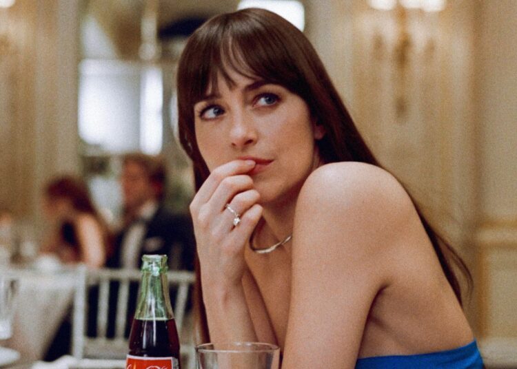 Dakota Johnson sits at a table with a look of mild upset in Materialists.