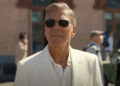 George Clooney as Jay Kelly, watches from behind shades as his daughter drives away on a bus. .