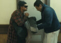 Benicio del Toro as Sensei St. Carlos bowing to Leonardo DiCaprio as Bob Ferguson in a hallway in One Battle After Another