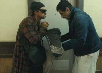 Benicio del Toro as Sensei St. Carlos bowing to Leonardo DiCaprio as Bob Ferguson in a hallway in One Battle After Another