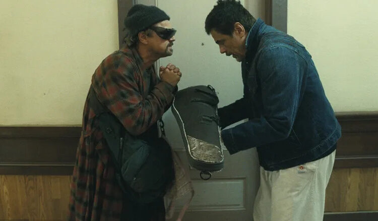 Benicio del Toro as Sensei St. Carlos bowing to Leonardo DiCaprio as Bob Ferguson in a hallway in One Battle After Another