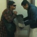 Benicio del Toro as Sensei St. Carlos bowing to Leonardo DiCaprio as Bob Ferguson in a hallway in One Battle After Another