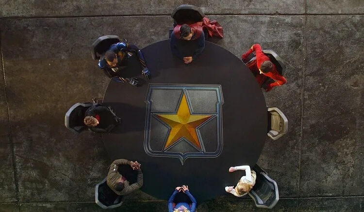 The seven members of The League assembles around a table in Crisis on Infinite Earths: Part Five