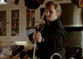 Denis Leary looking angry while on the phone and spraying water from a sink in The Ref.