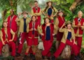 ITV 10 people can be seen wearing various outfits of red and khaki green, with some wearing large khaki hats. They are posed in front of a jungle backdrop as part of the announcement for the new cast of I'm a Celebrity...Get Me Out of Here!