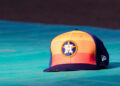 An orange and blue ball cap with the Houston Astros logo on it while it rests on a blue table.