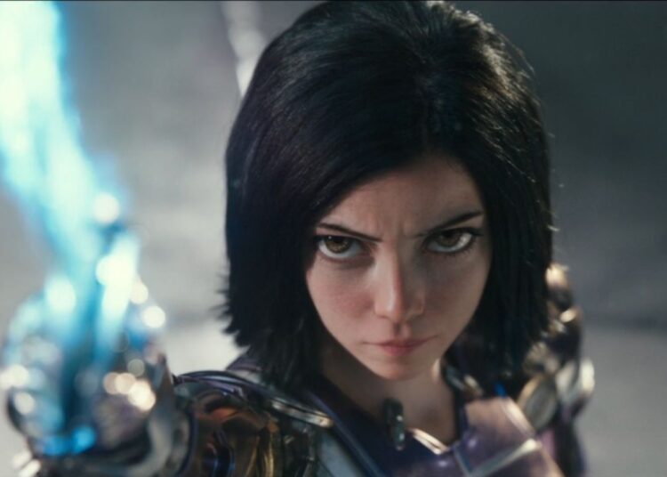 Rosa Salazar looks up defiantly while holding her sword skyward in Alita: Battle Angel.
