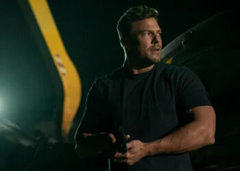 Alan Ritchson as Reacher holding a pistol