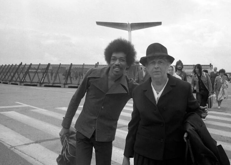 Jimi Hendrix poses with a fellow passenger on the runway as he arrives at Hamburg airport on Sept. 5, 1970. (AP Photo/Helmuth Lohmann)