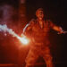 Mahershala Ali as Kincaid lighting up a flare in front of the mutant dinosaur in Jurassic World Rebirth