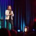 Kathleen Madigan standing on stage holding a mic