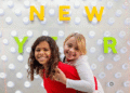 Two kids play piggy-back in front of a Happy New Year sign. (Courtesy photo)