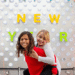 Two kids play piggy-back in front of a Happy New Year sign. (Courtesy photo)