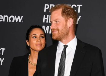 Meghan Markle admiring Prince Harry as they both wearing matching black outfits.