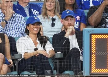 Meghan sat court-side at a World Series Baseball game with Prince Harry opting for an effortlessly chic ensemble of a crisp white Givenchy shirt, previously worn at the Endeavour Fund Awards, Veronica Beard jeans and a baseball hat