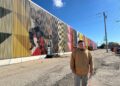 Photo of Mauricio Martinez with his mural in Oshkosh.