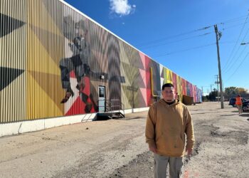 Photo of Mauricio Martinez with his mural in Oshkosh.