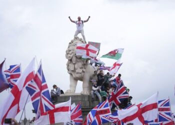 A demonstrator stands on the head of the South Bank lion that sits on the side of the Westminster Bridge, during a Tommy Robinson-led Unite the Kingdom march and rally in London, Saturday, Sept. 13, 2025. (AP Photo/Joanna Chan)