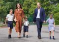 Prince William and his wife Catherine pictured with their children, linking hands, in school uniforms