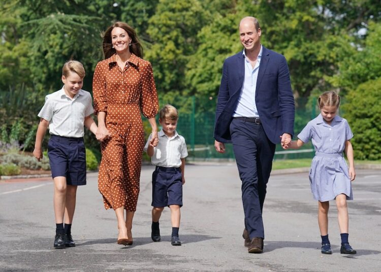 Prince William and his wife Catherine pictured with their children, linking hands, in school uniforms