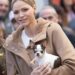 Princess Charlene holding a dog wearing a tan coat