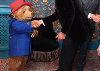 The Prince of Wales shakes hands with Paddington Bear from the London stage musical, alongside Tom Fletcher from McFly